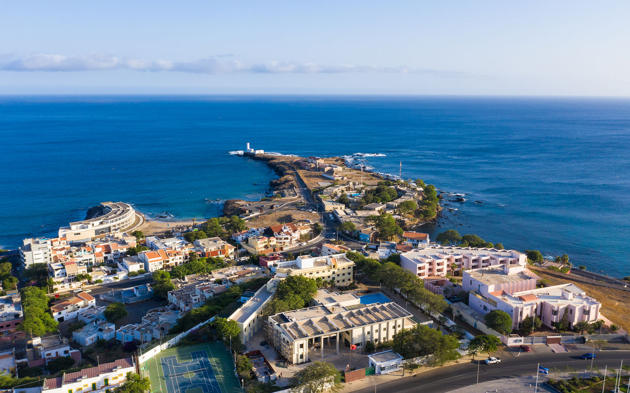 Explore Hotéis na Cidade da Praia com uma vista aérea sobre a costa urbana e o oceano azul de Cabo Verde