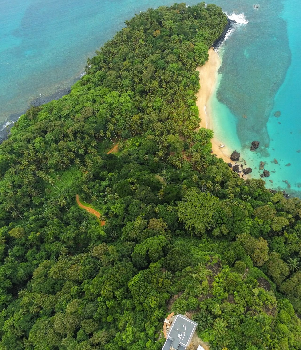 Explore Hotéis em São Tomé com uma vista aérea de floresta tropical densa e praia de águas turquesa claras