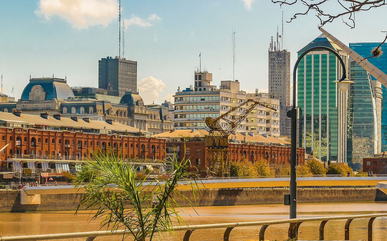 Paisagem urbana de Buenos Aires com o bairro portuário de Puerto Madero, com edifícios altos e um rio Prata