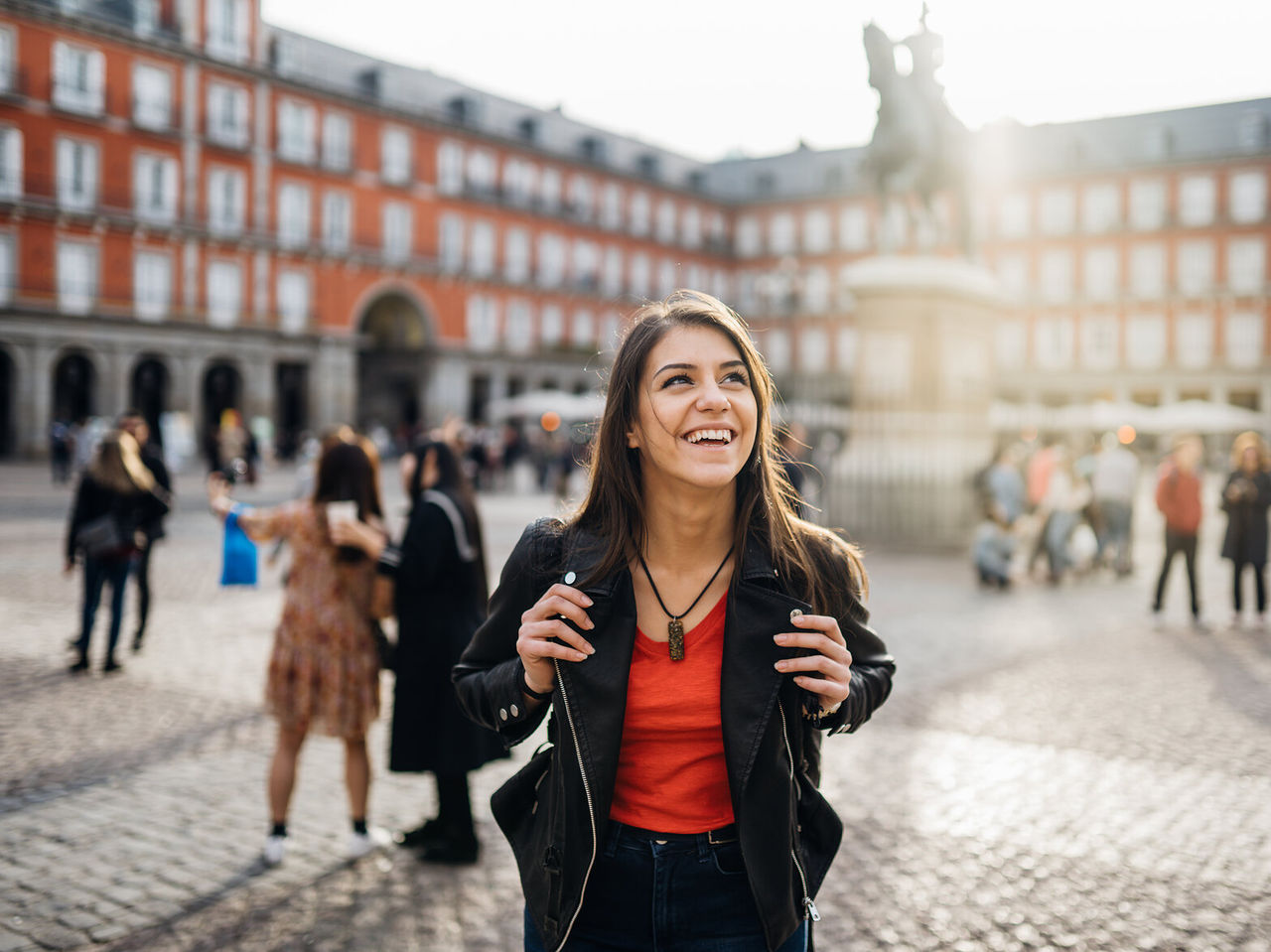Explore Hotéis em Madrid, onde visitantes passeiam pela praça iluminada junto à estátua no centro histórico