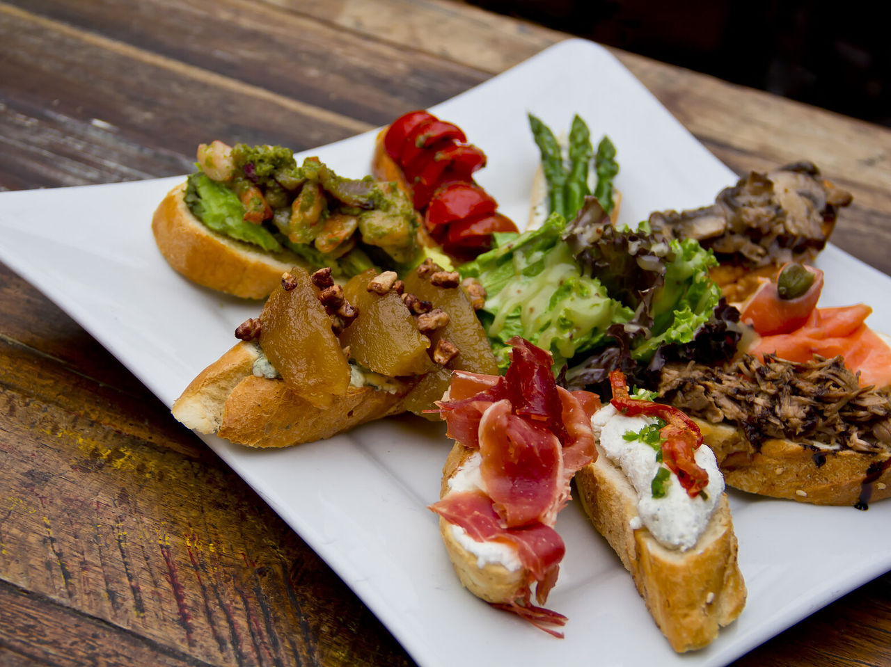 Explore Hotéis em Madrid apresentando prato com tapas variadas, legumes grelhados, salada e pão artesanal