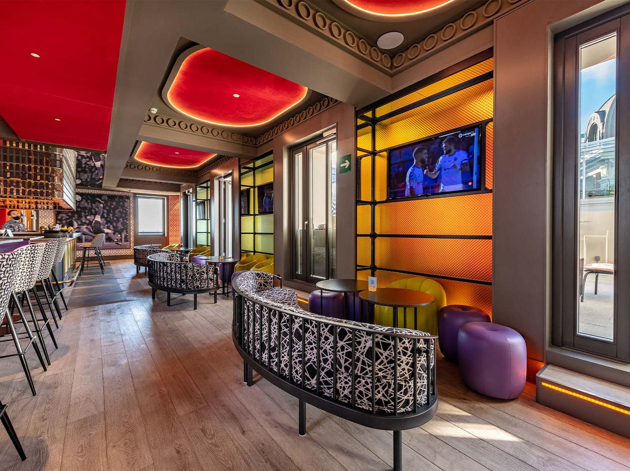 O bar Sports Bar, do Hotel no Centro de Madrid, em Espanha, tem um espaço colorido com diversos bancos altos, sofás e pufes