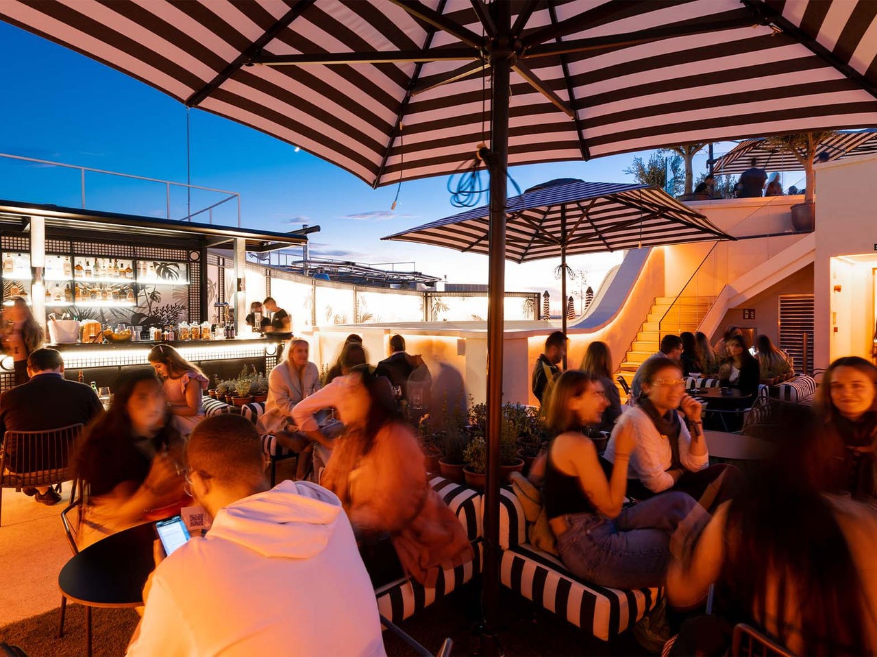 O bar Rooftop Bar, do Hotel no Centro de Madrid, em Espanha, tem um espaço amplo com chapéus, mesas, cadeiras e sofás