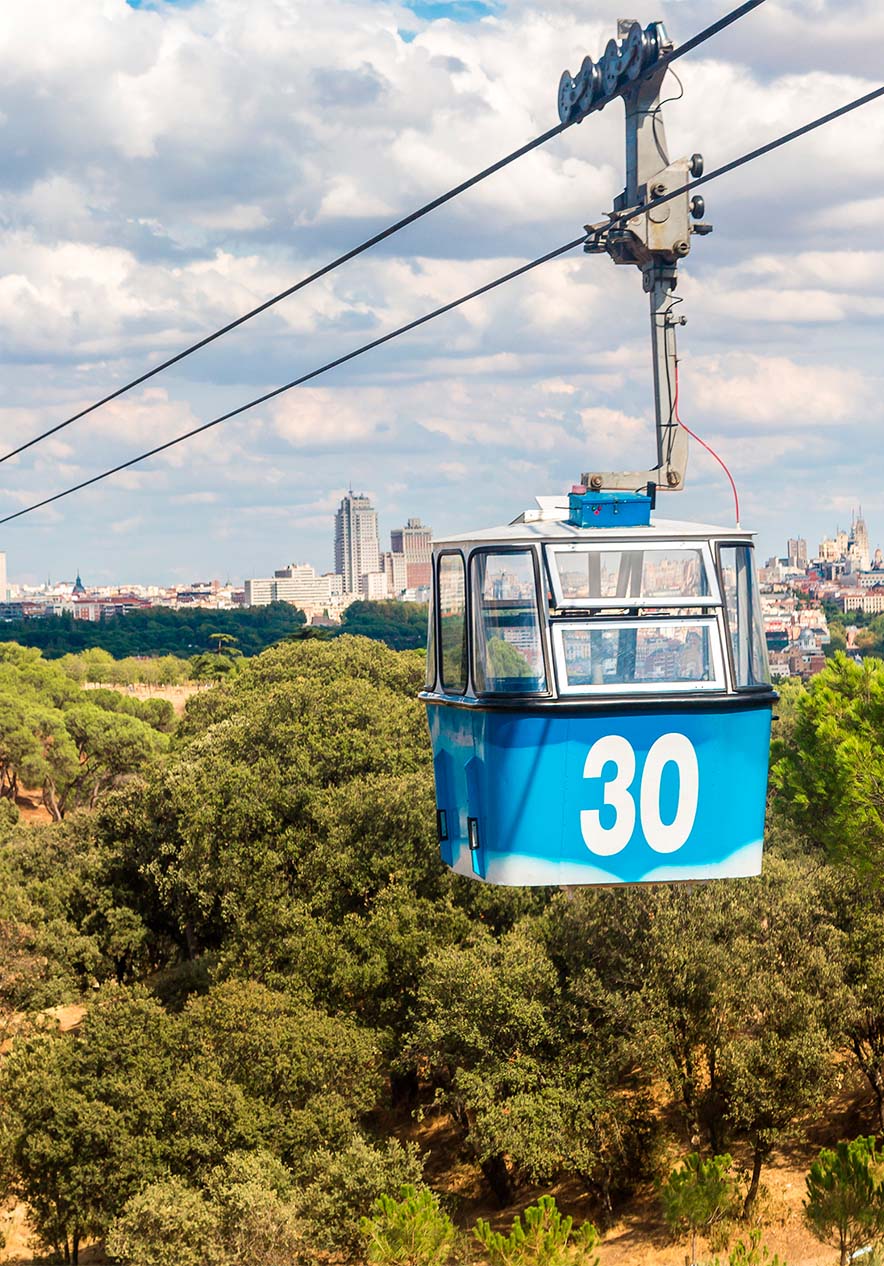 Teleférico azul com o número 30 por cima da cidade de Madrid e de várias árvores