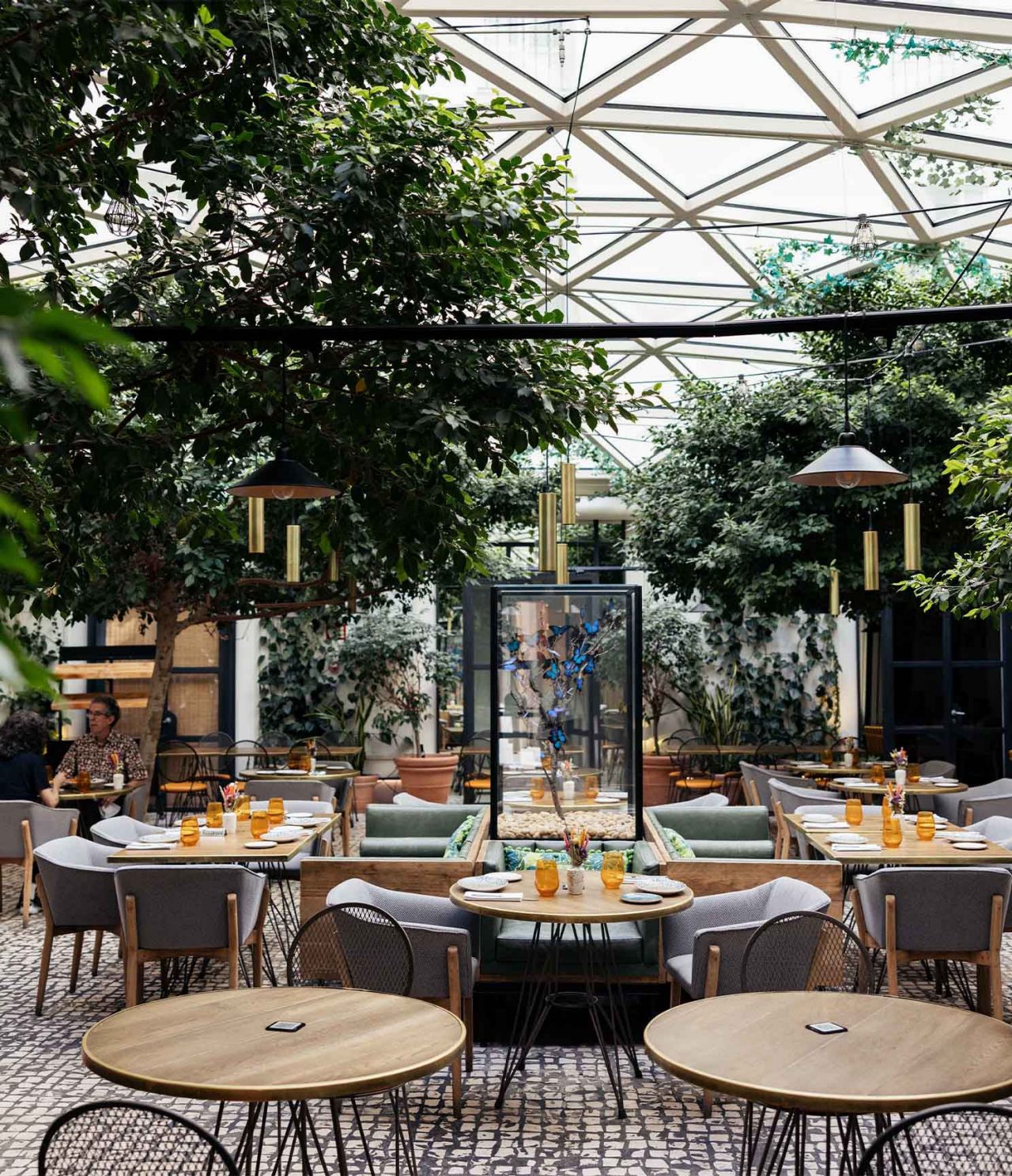 O restaurante Café de La Plaza, do Hotel no Centro Histórico de Madrid, tem um pátio com várias mesas e vegetação verde