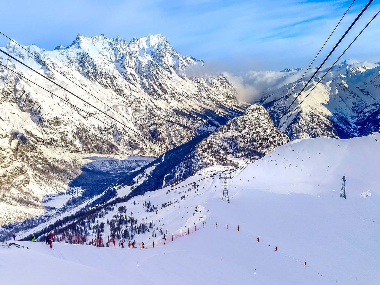 Paisagem nevada dos Alpes Italianos com cabos de teleférico, encostas de esqui e vale montanhoso ao fundo