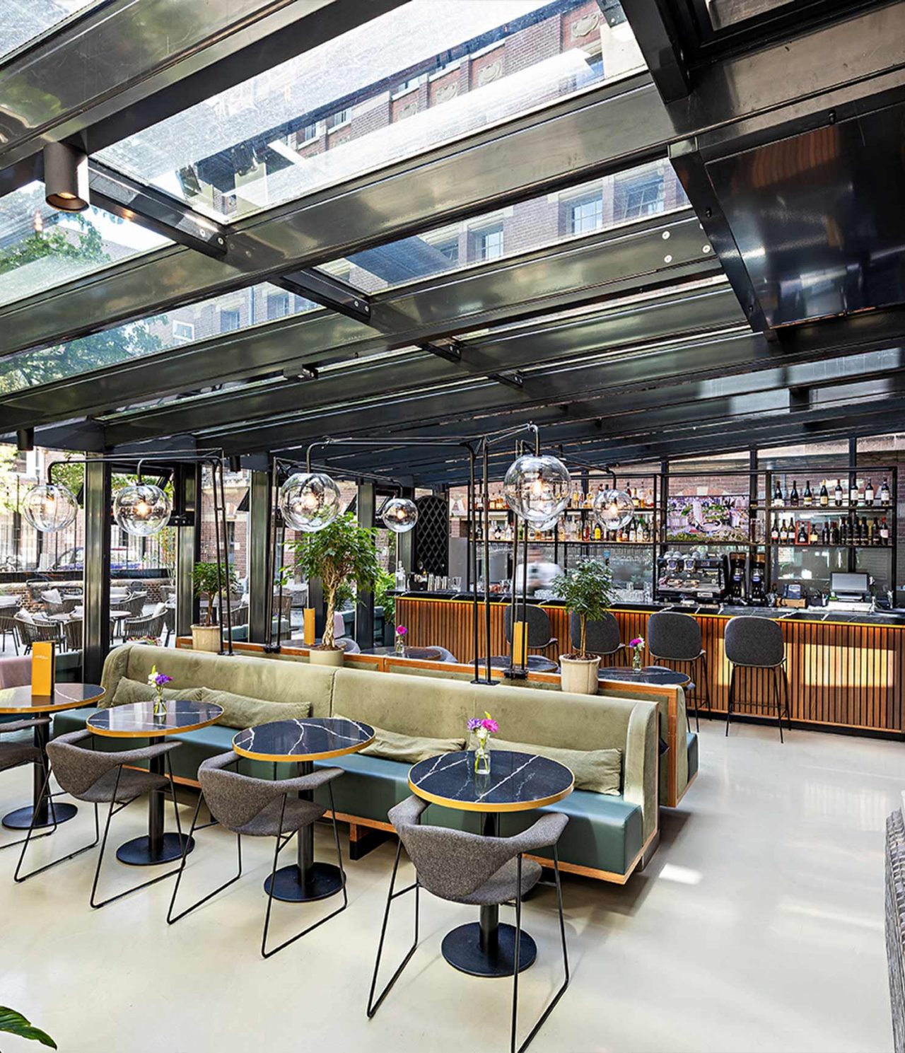 Bar do Pestana Amsterdam Riverside, Hotel 5 Estrelas em Amesterdão, com mesas elegantes e teto de vidro