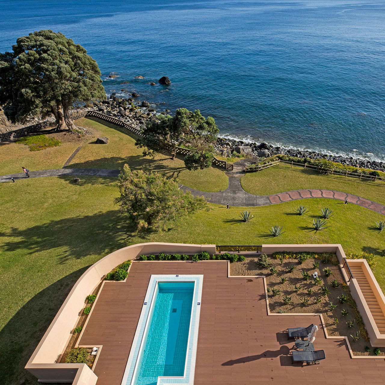 Vista de cima para a piscina do Pestana Bahia Praia, rodeada de jardins e com o mar em redor