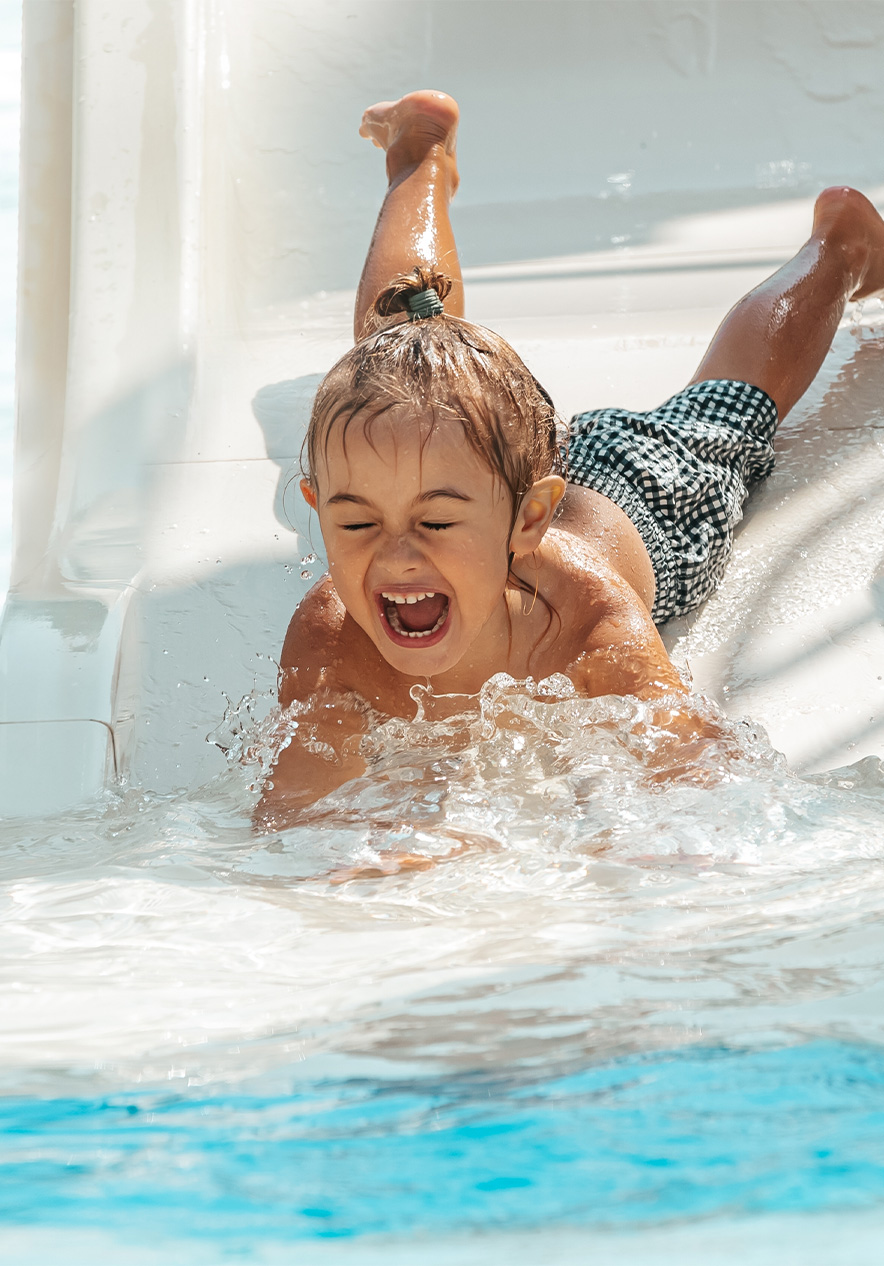 Criança desce sorridente de um escorrega de água, no Slide & Splash, no Algarve