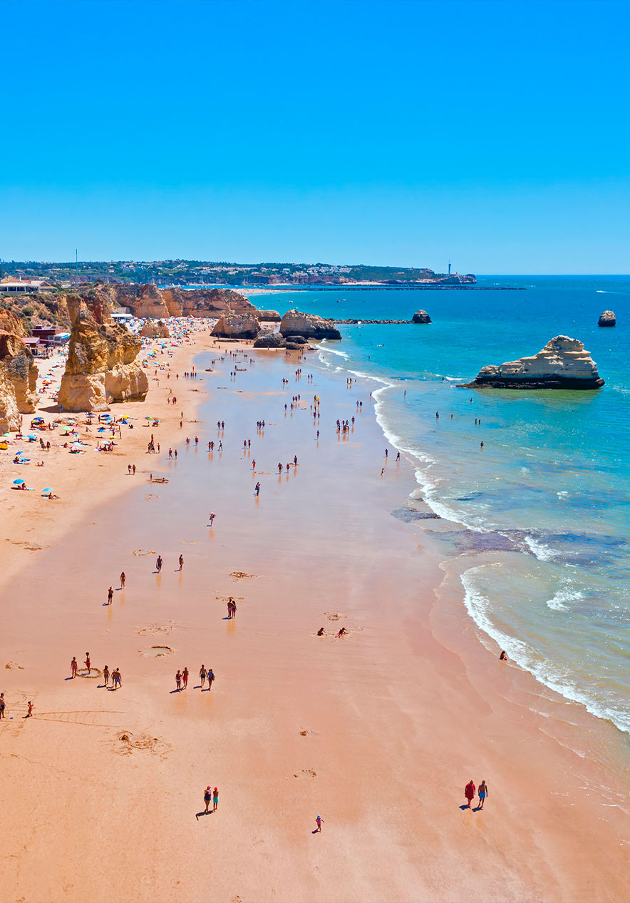 Visite a Praia da Rocha com várias rochas espalhadas pelo areal que vão ao encontro da água azul do Algarve