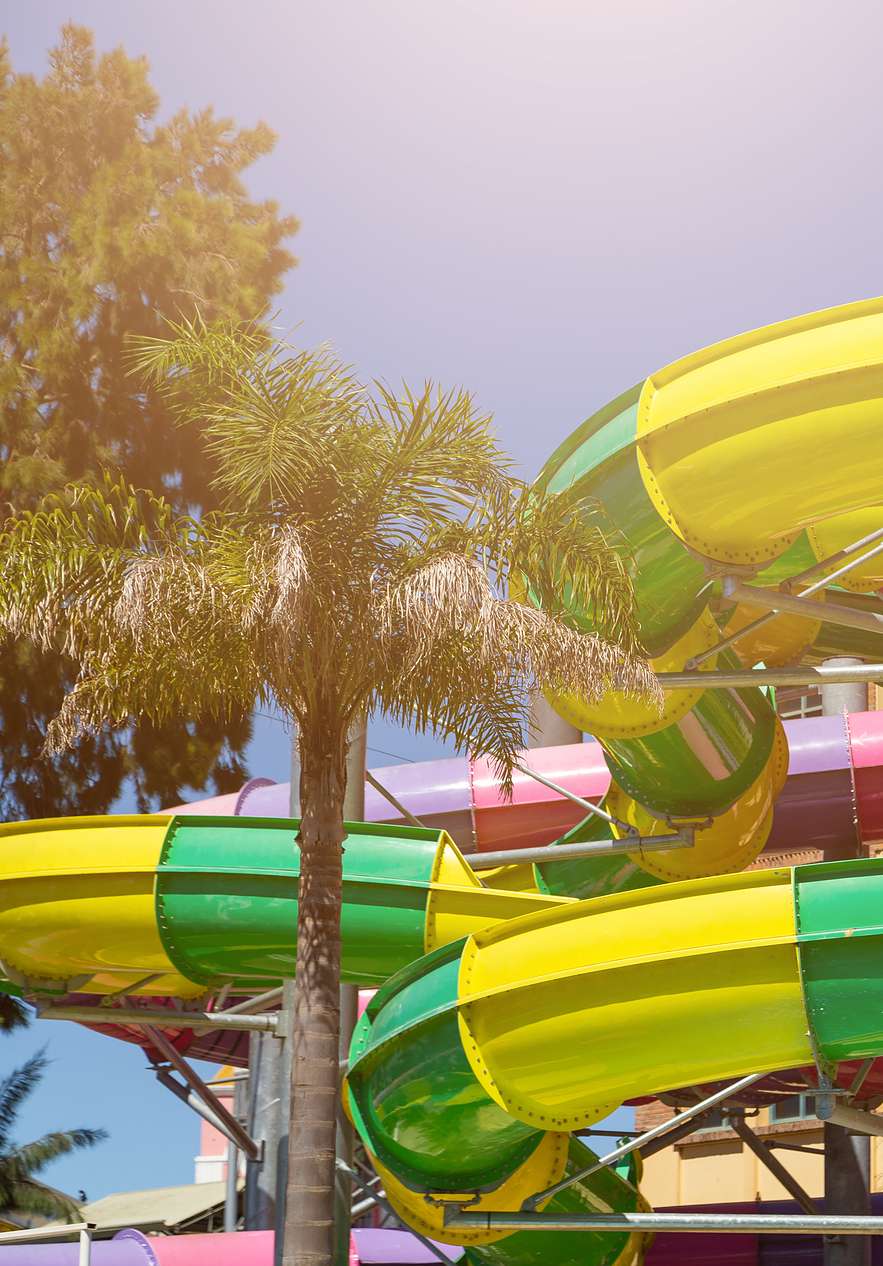 Parque aquático Aquashow com escorregas coloridos e palmeiras sob céu azul perto do Pestana Vila Sol, Hotel com Golfe e Spa no Algarve