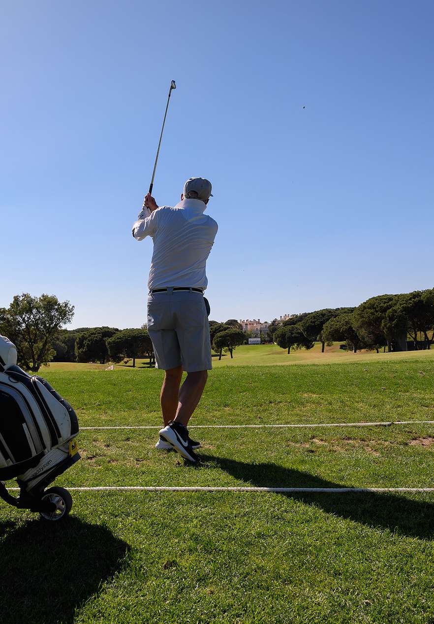 Homem a praticar tacadas de golfe num campo verde sob céu limpo, perto do Pestana Vila Sol, Hotel com Golfe e Spa no Algarve
