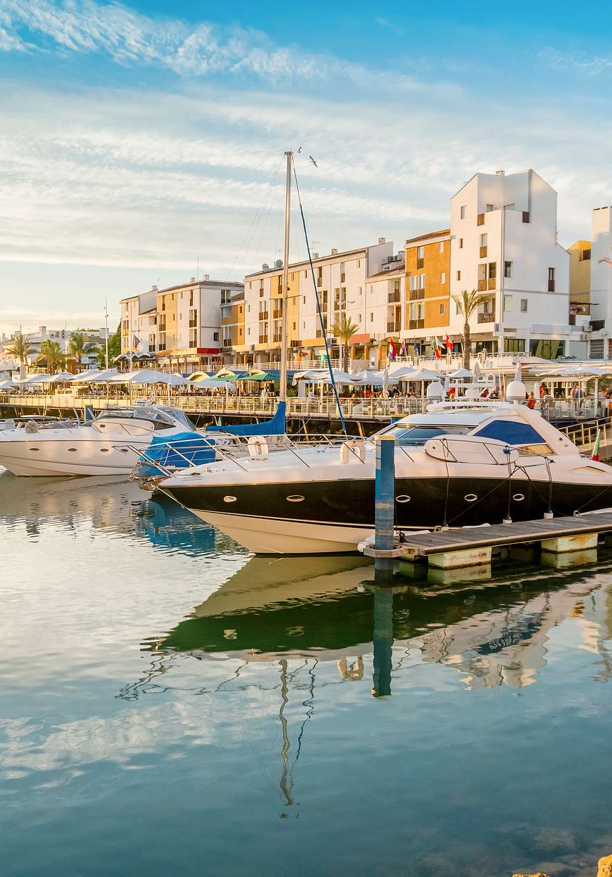 Marina de Vilamoura no Algarve ao pôr do sol, com barcos ancorados de diversos tamanhos e estilos e água calma