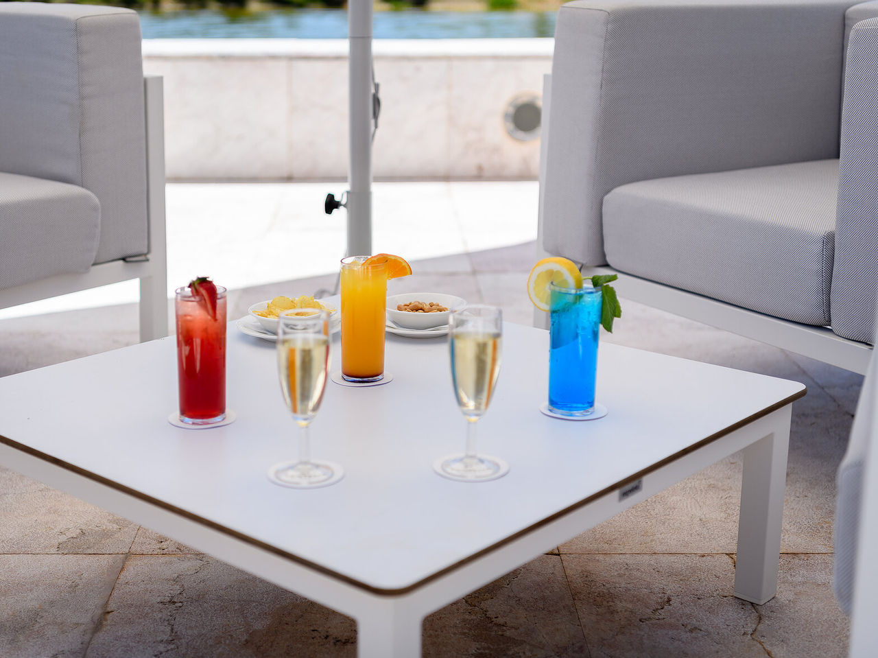 Bar do Pestana Vila Sol, Hotel com Golfe e Spa no Algarve, com mesa branca servindo cocktails coloridos e taças de espumante junto à piscina