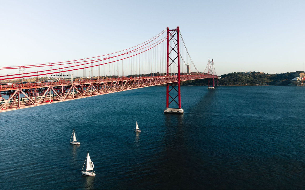Vista panorâmica da cidade de Lisboa, com o Rio Tejo com vários barcos e a ponte 25 de Abril