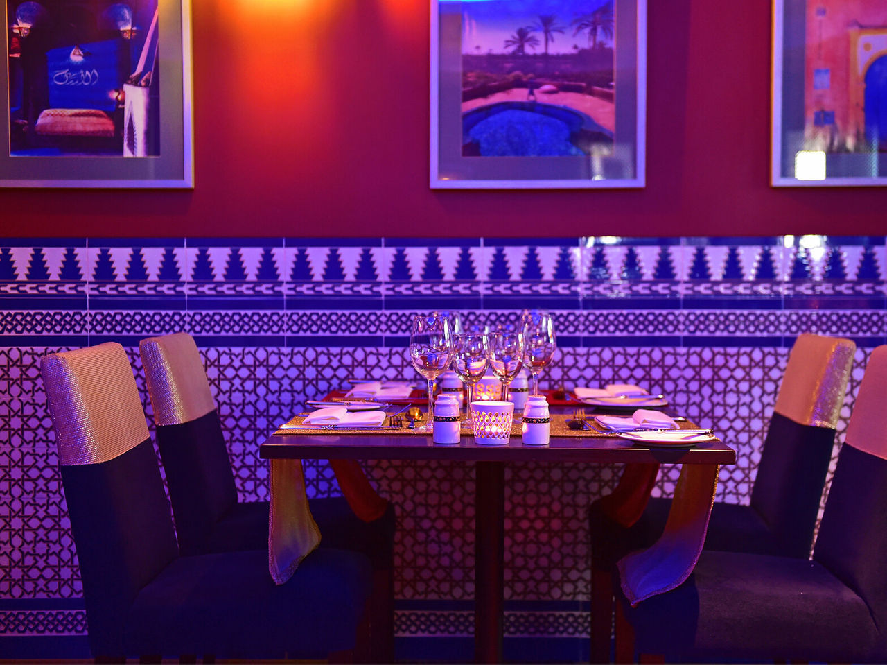 O restaurante Au Tagine, do Hotel 5 Estrelas no Funchal, na Madeira, tem uma mesa, com quatro cadeiras, e quadros na parede