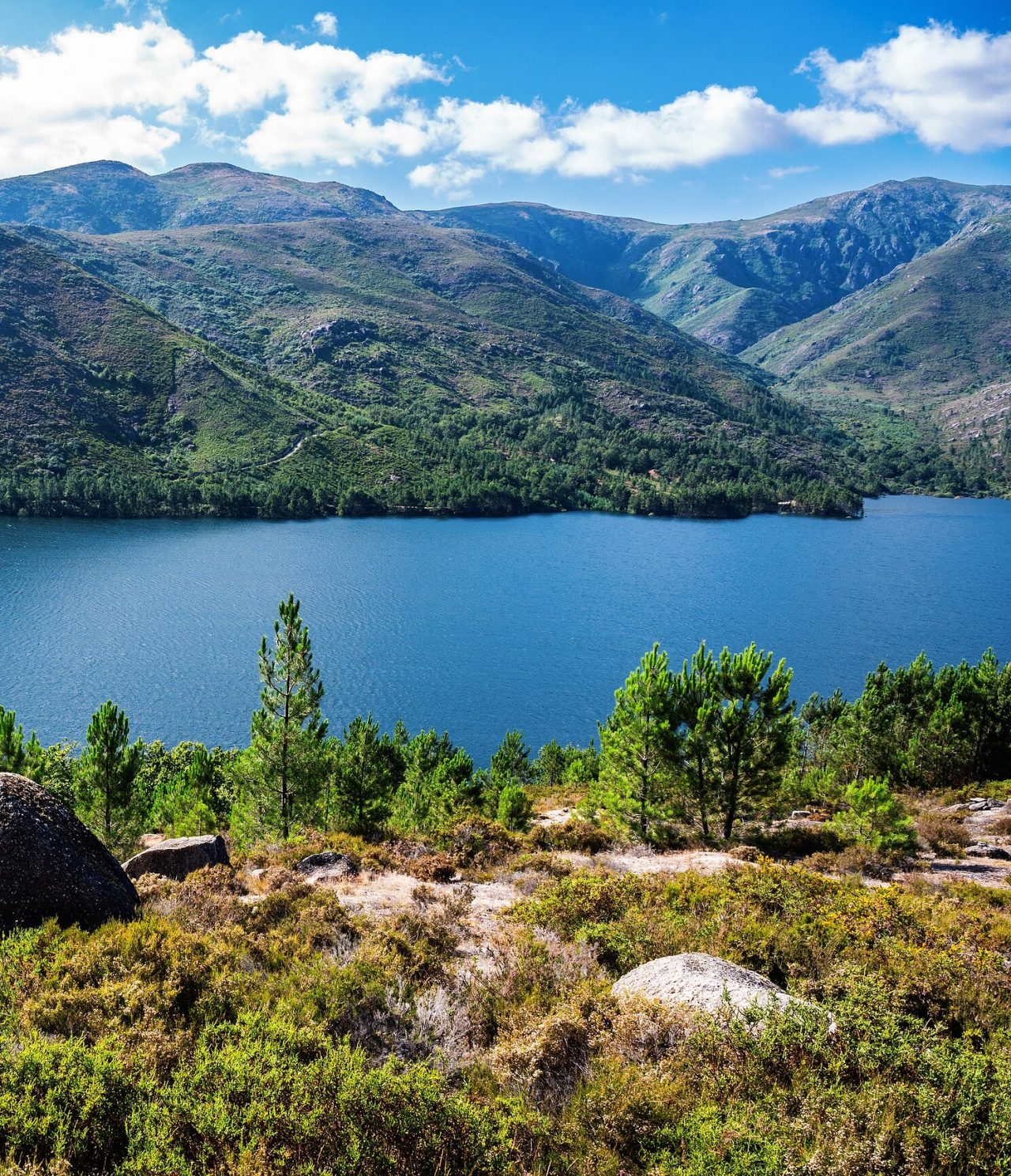 Explore Hotéis no Norte de Portugal com vista para lago azul entre montanhas verdes sob céu com nuvens