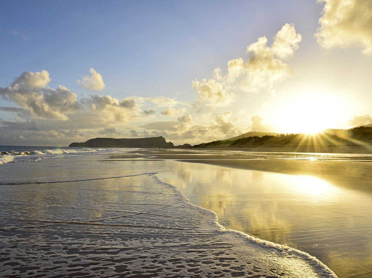 Explore Hotéis em Porto Santo com vista para praia ampla ao pôr do sol refletido na areia e no mar