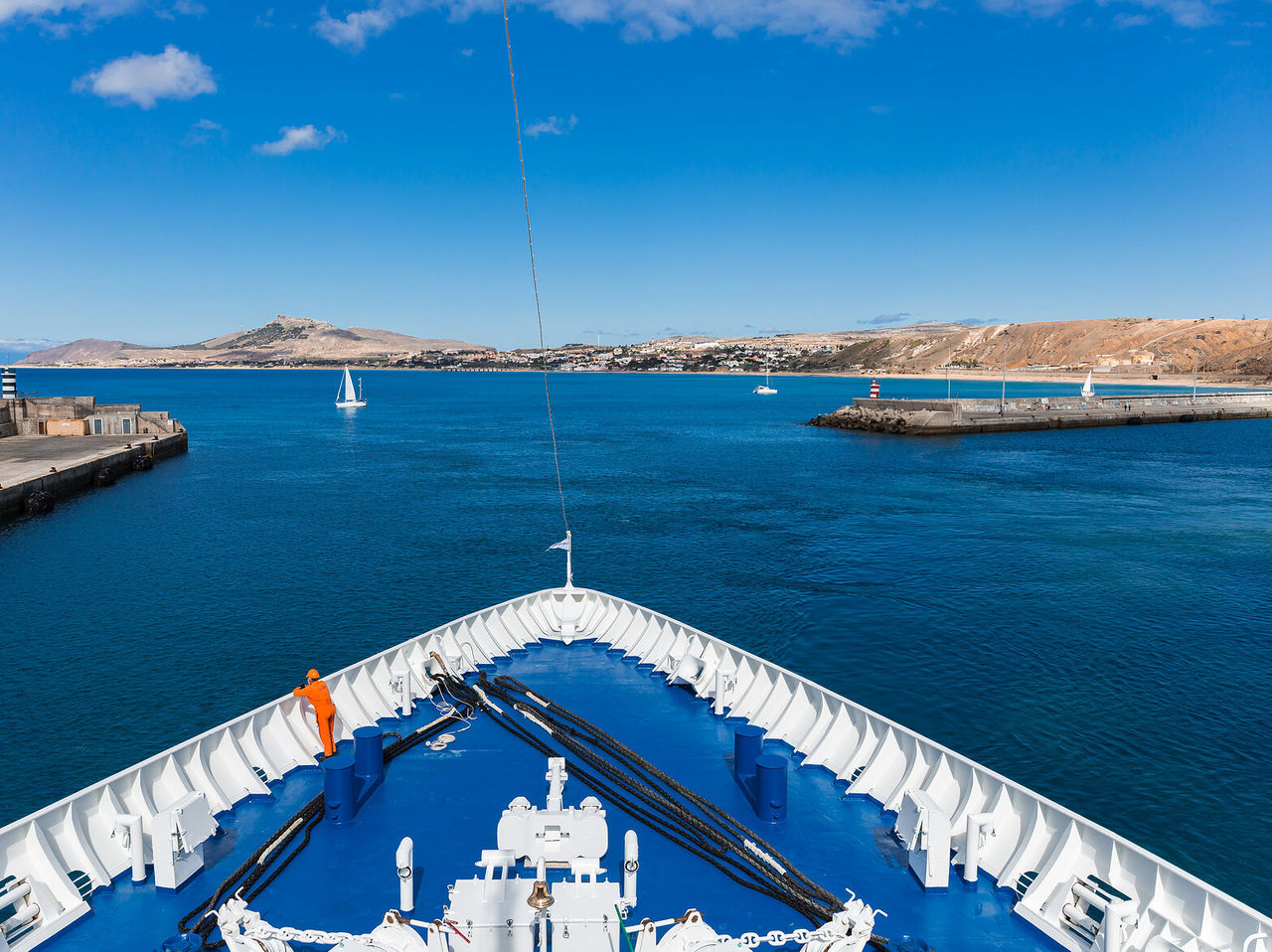 Explore Hotéis em Porto Santo com vista sobre a proa de um navio a entrar no porto junto ao mar azul