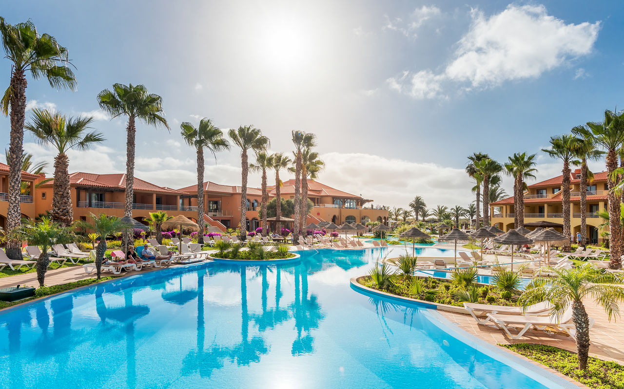 Piscina exterior do Pestana Porto Santo, Resort de 5 Estrelas no Porto Santo, com várias palmeiras e espreguiçadeiras
