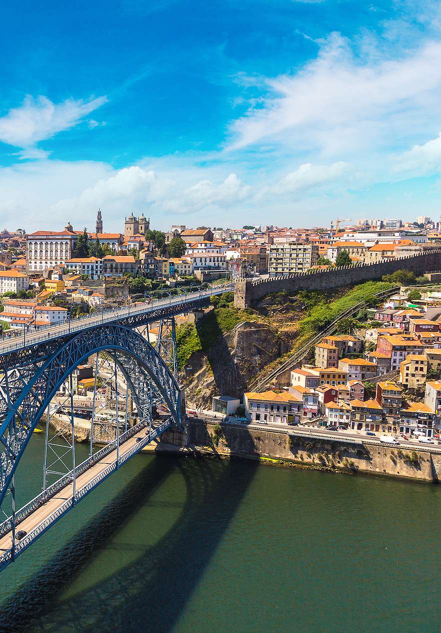 Vista aérea do Rio Douro junto ao Pestana Palácio do Freixo, Hotel 5 Estrelas no Porto, Monumento Nacional, mostrando a ponte metálica e as casas históricas da cidade sob um céu azul