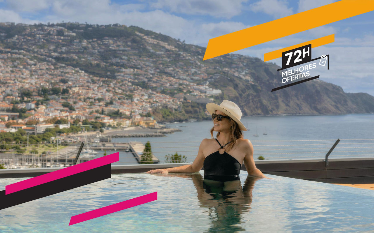 Mulher relaxa numa piscina infinita com vista para o mar e montanhas, sob céu parcialmente nublado