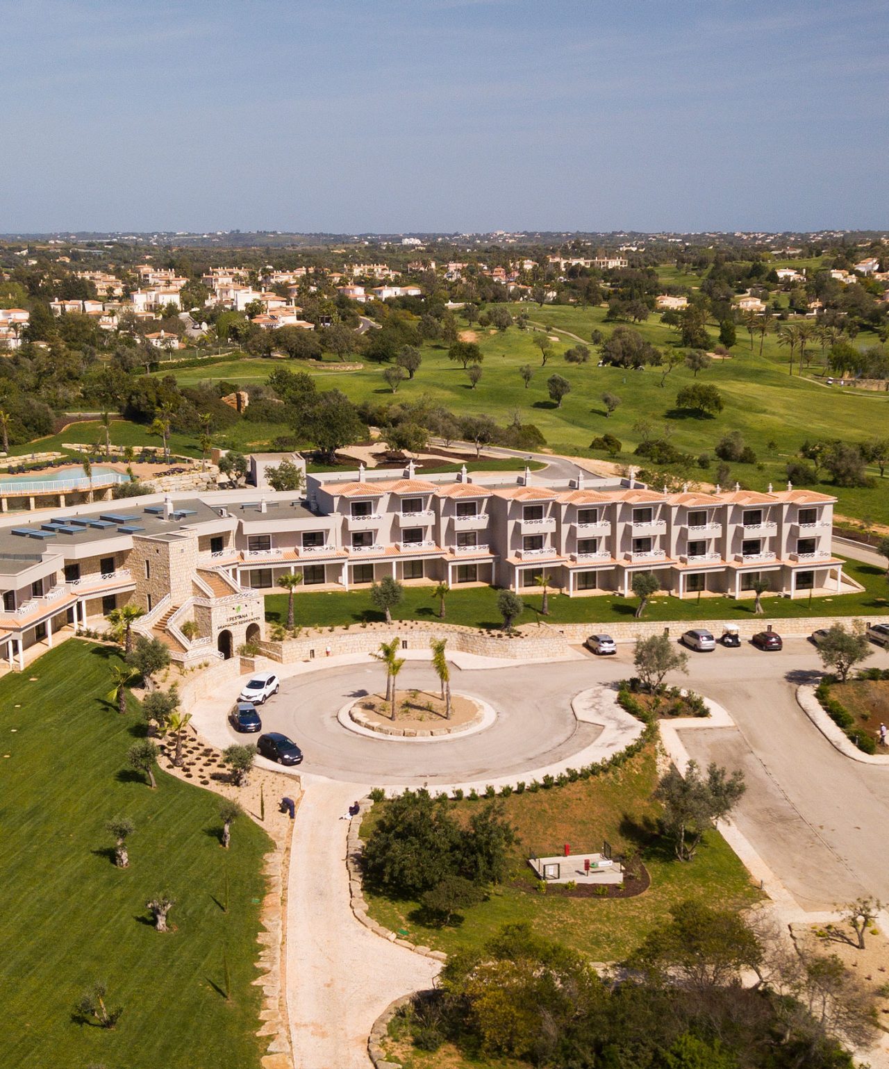 Vista aérea do Pestana Residences, edifício moderno rodeado por jardins e campo de golfe