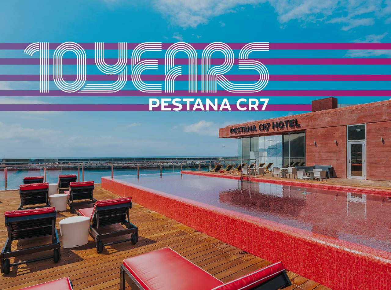 Banner dos 10 anos Pestana CR7 sobre piscina no terraço com espreguiçadeiras vermelhas e vista para o mar