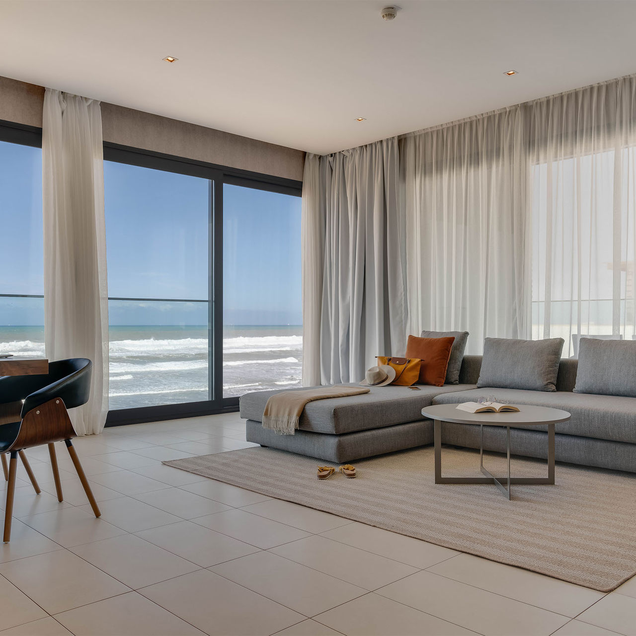 Room with sea view, a cozy comfortable sofa with chaise lounge, and a table with modern design chairs