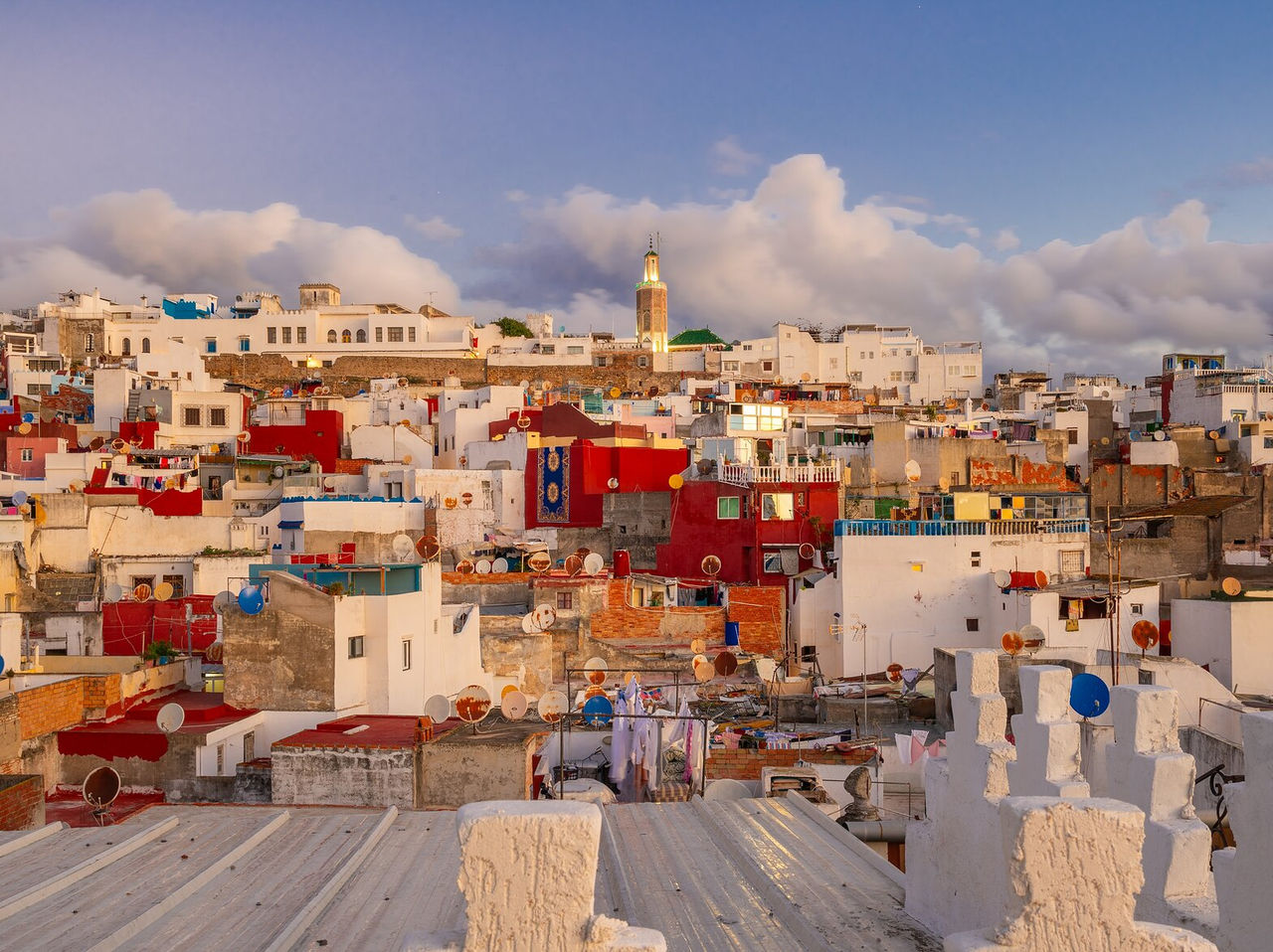 Explore Hotéis em Tânger com vista sobre os telhados coloridos e a torre iluminada ao entardecer urbano