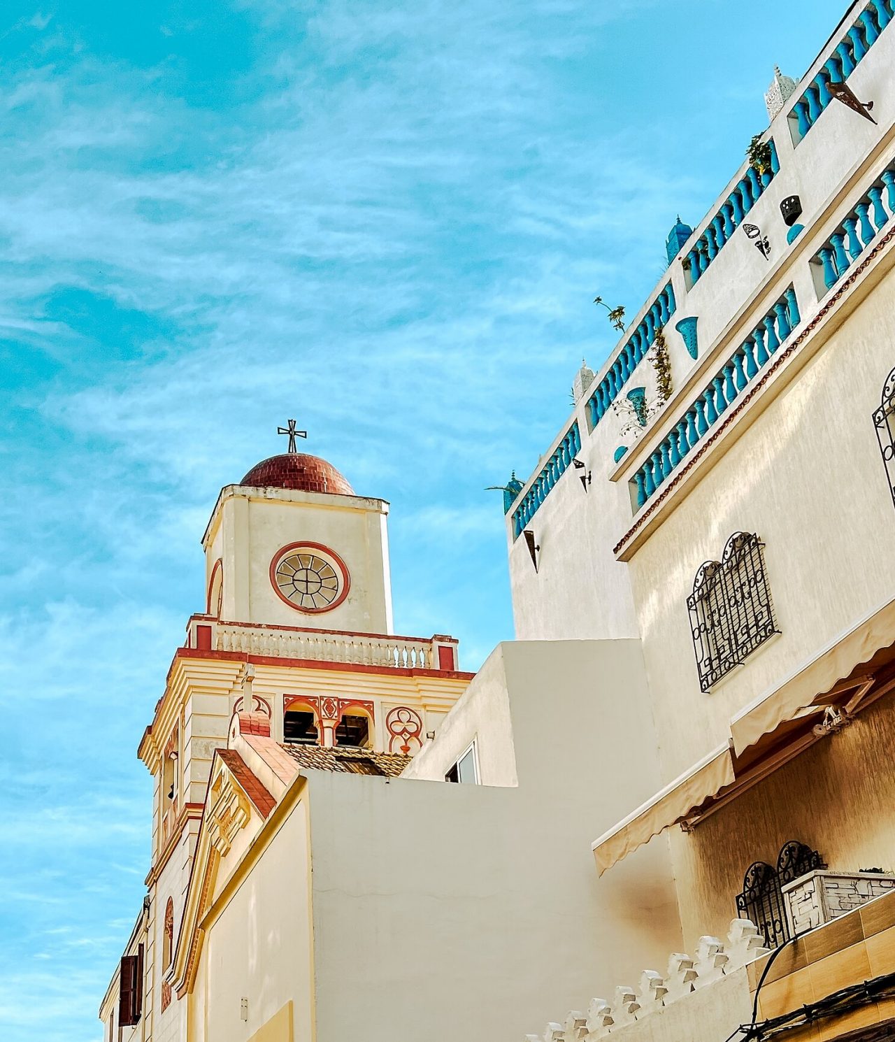 Explore Hotéis em Tânger com vista para edifícios brancos e torre com cúpula vermelha sob céu azul claro