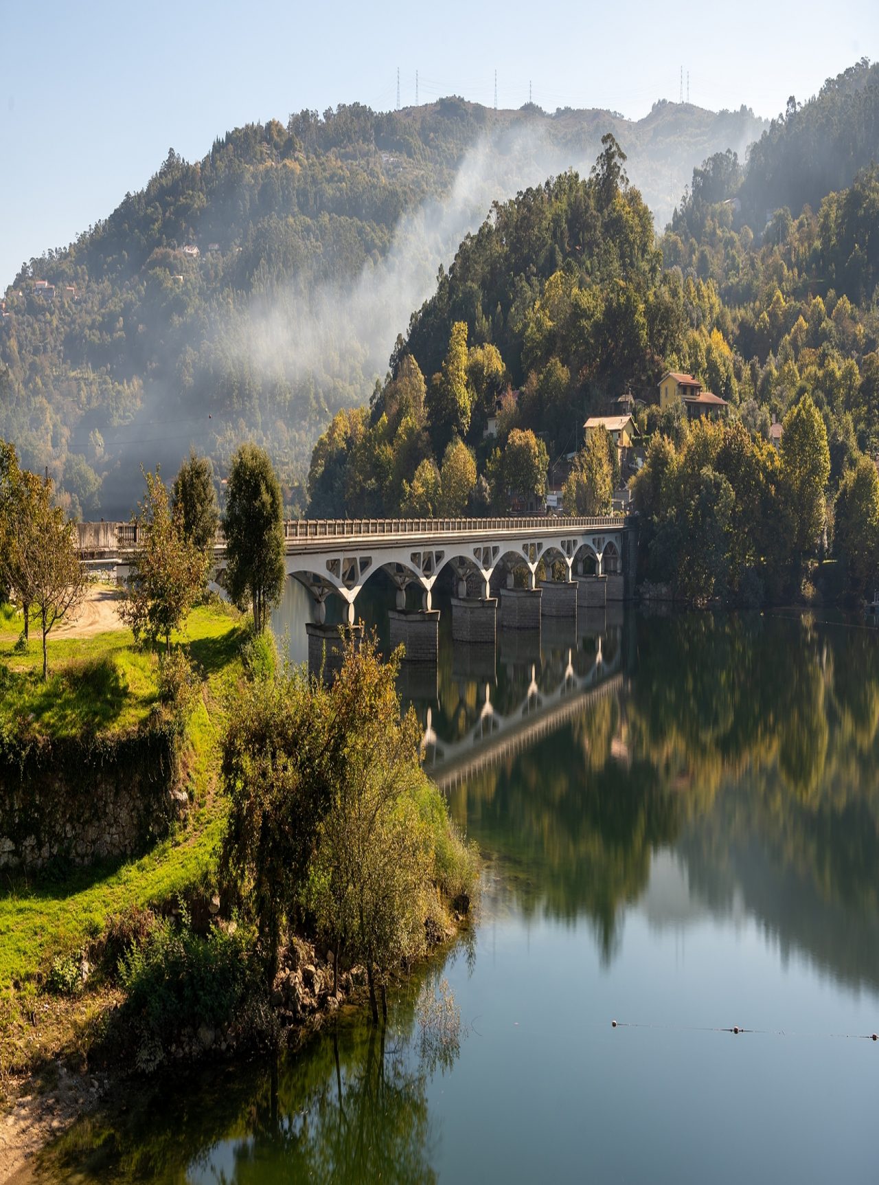 Landscape of northern Portugal with a stone bridge over a river, surrounded by green hills