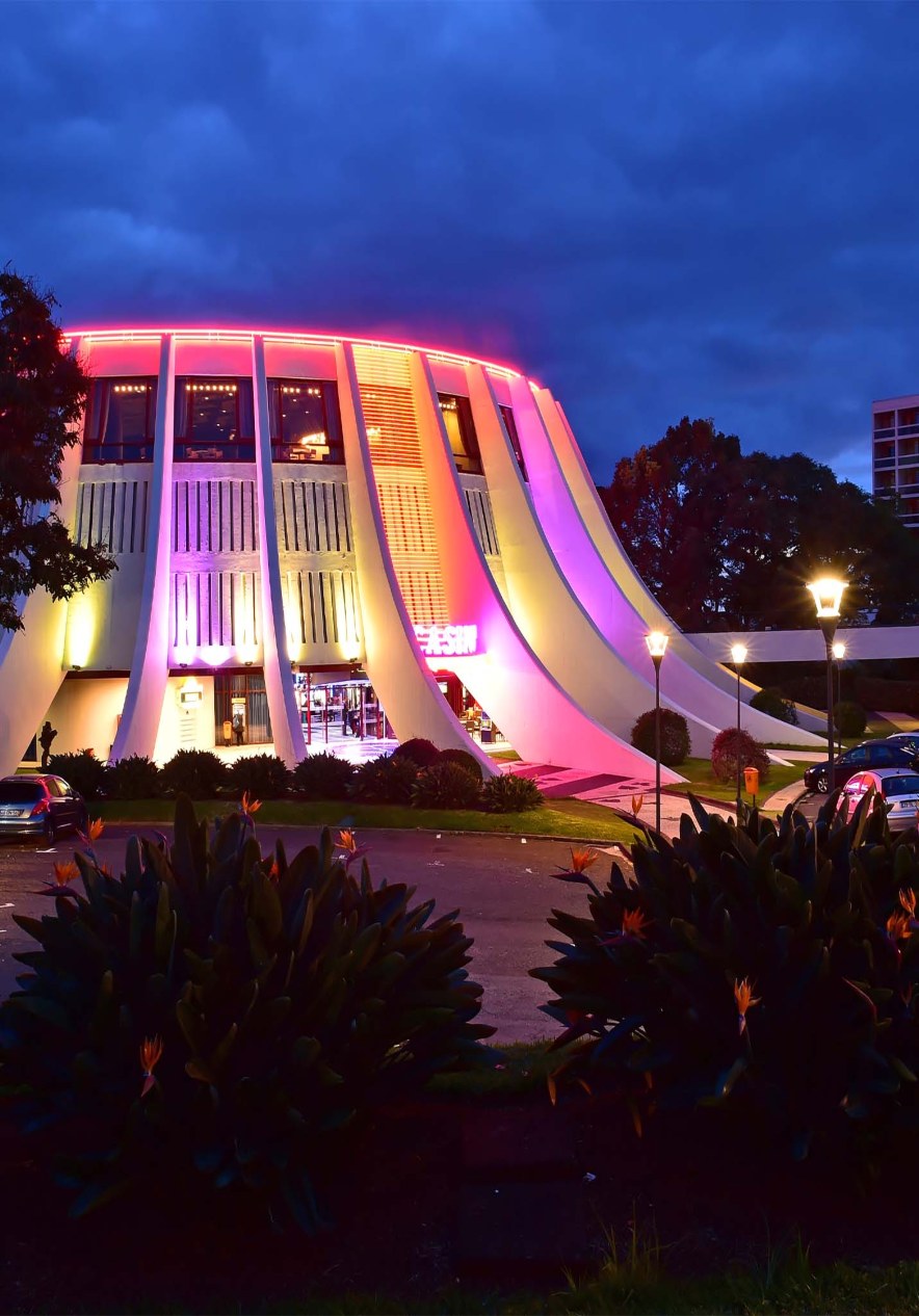 Cultural tour near Pestana Casino Park, 5-Star Hotel in Downtown Funchal, featuring a lit modern venue at dusk