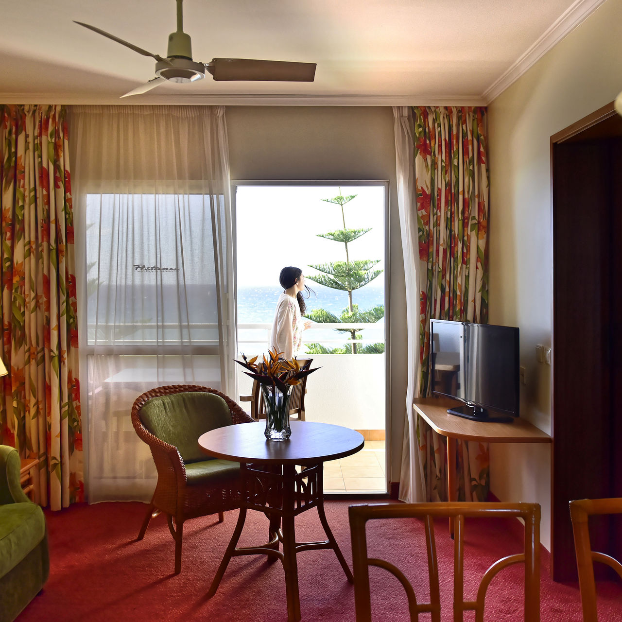 Interior view of a room at Pestana Ocean Bay All Inclusive, with a living room and a lady on the balcony