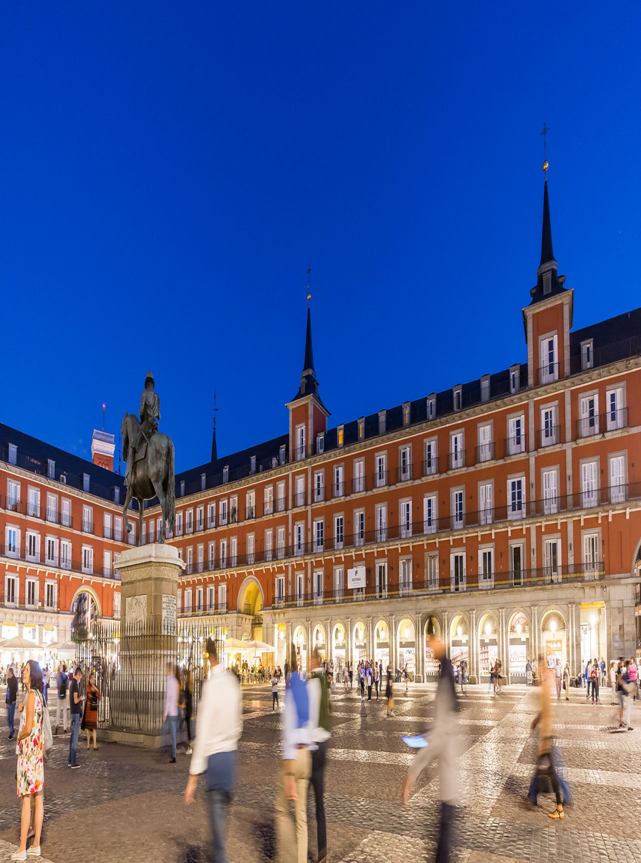 Plaza Mayor, in the historic center of Madrid, at night, with many tourists waljing around the Pestana Plaza Mayor is located
