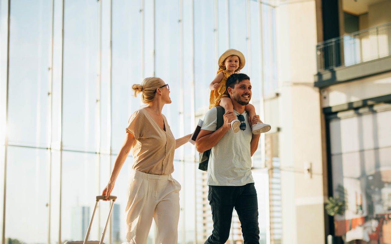 Smiling family with travel bags arriving at a Pestana Hotel Group hotel on a sunny day