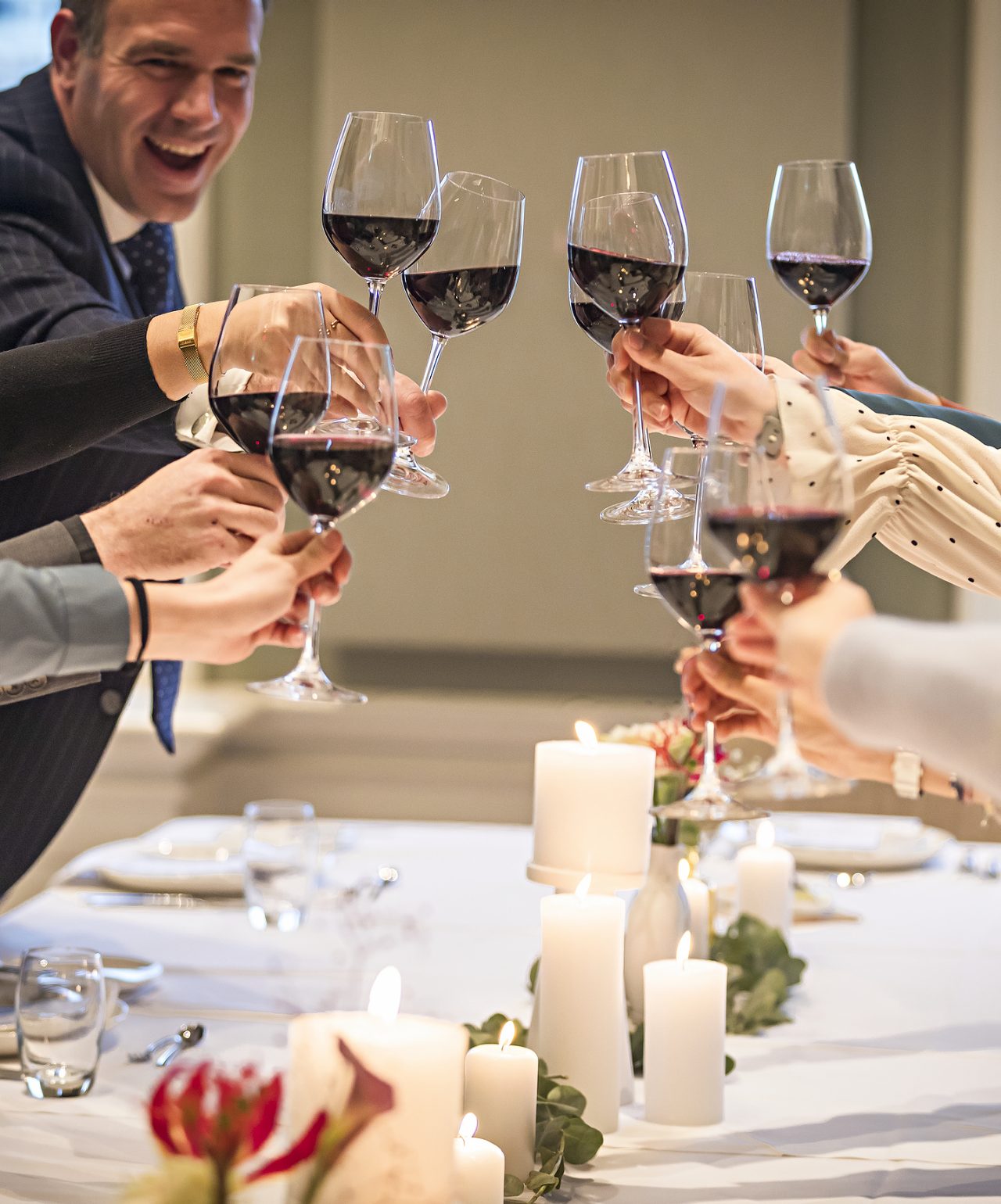 Guests toast with glasses of red wine at a wedding with elegant decor at Pestana Hotel Group